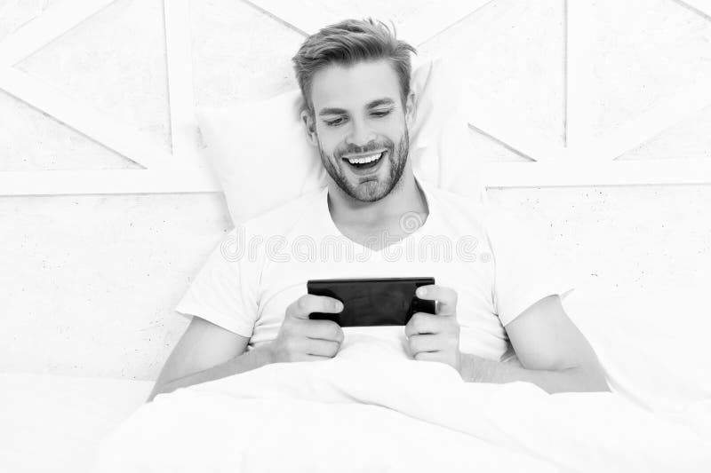 Ανδρικά στοιχήματα στο smartphone. Βιντεοπαιχνίδια online. Άνδρας που παρακολουθεί τηλέφωνο. Άντρας που ποντάρει στην κρεβατοκάμαρ στοκ φωτογραφία με δικαίωμα ελεύθερης χρήσης