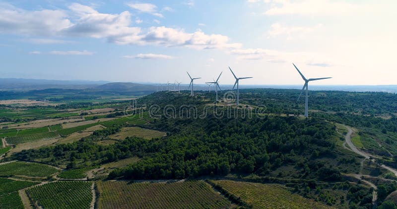 Ανεμοστρόβιλοι σε έναν λόφο με τους τομείς και τις αμπέλους