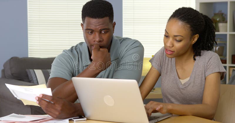 Ανησυχημένο ζεύγος αφροαμερικάνων που κοιτάζει μέσω των λογαριασμών on-line