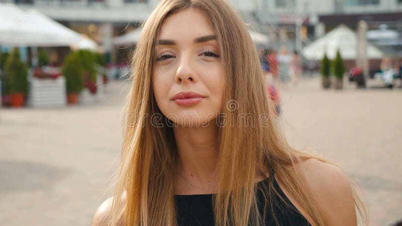 Ανοικτό καφέ μαλλιαρή νέα γυναίκα προσώπου που εξετάζει τη κάμερα κοντά επάνω Όμορφη γυναίκα πορτρέτου στο αστικό υπόβαθρο οδών π φιλμ μικρού μήκους