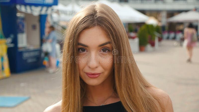 Ανοικτό καφέ μαλλιαρή νέα γυναίκα προσώπου που εξετάζει τη κάμερα κοντά επάνω Όμορφη γυναίκα πορτρέτου στο αστικό υπόβαθρο οδών π απόθεμα βίντεο