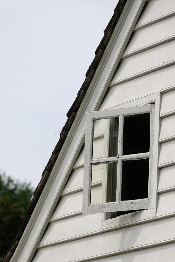 Partially open attic widow of vintage white cottage. Partially open attic widow of vintage white cottage.