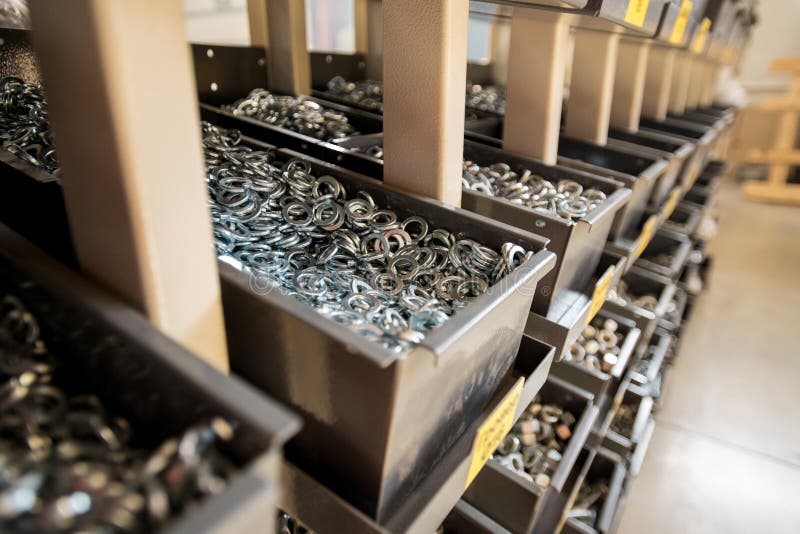 Stacks of iron or metallic spare parts for industrial machines in large steel containers standing in row in storage room. Stacks of iron or metallic spare parts for industrial machines in large steel containers standing in row in storage room