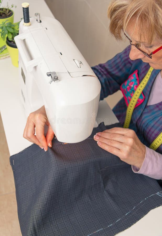 Ανώτερη seamstress γυναίκα που εργάζεται στη ράβοντας μηχανή στοκ εικόνα με δικαίωμα ελεύθερης χρήσης Ανώτερη seamstress γυναίκα που εργάζεται στη ράβοντας μηχανή στοκ εικόνα με δικαίωμα ελεύθερης χρήσης
