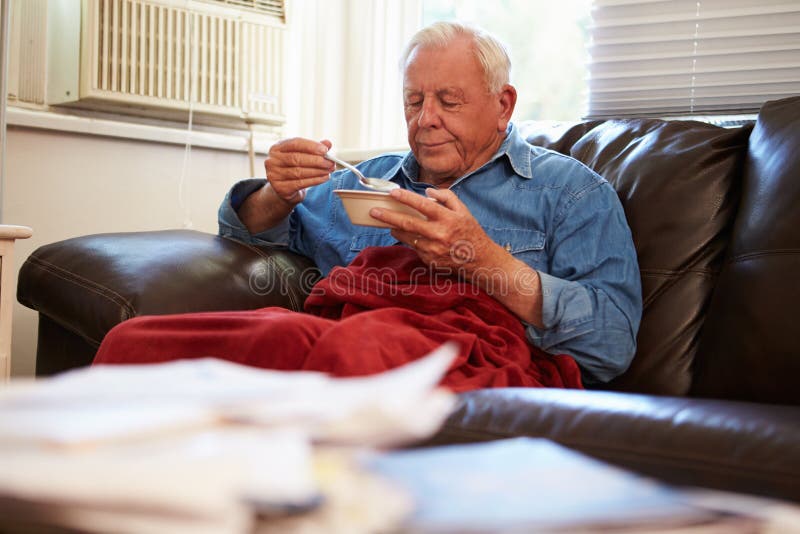 Unhappy Senior Man With Poor Diet Keeping Warm Under Red Blanket. Unhappy Senior Man With Poor Diet Keeping Warm Under Red Blanket