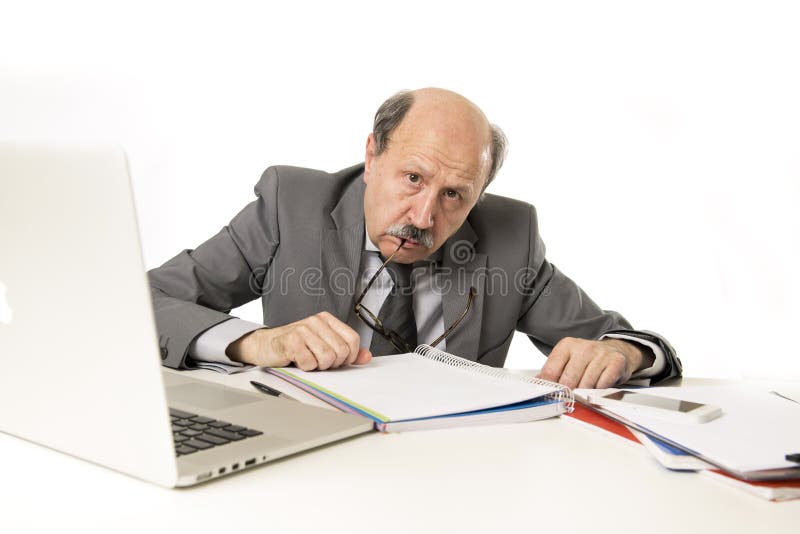 Senior mature busy business man with bald head on his 60s working stressed and frustrated at office computer laptop desk looking tired and overwhelmed in job problems and overwork concept. Senior mature busy business man with bald head on his 60s working stressed and frustrated at office computer laptop desk looking tired and overwhelmed in job problems and overwork concept