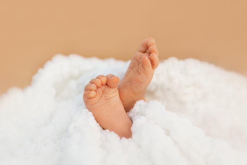 Αξιολάτρευτα μωρουδιακά πόδια τυλιγμένα σε μια λευκή κουβέρτα, μια ιδέα μητρότητας και παιδικής φροντίδας