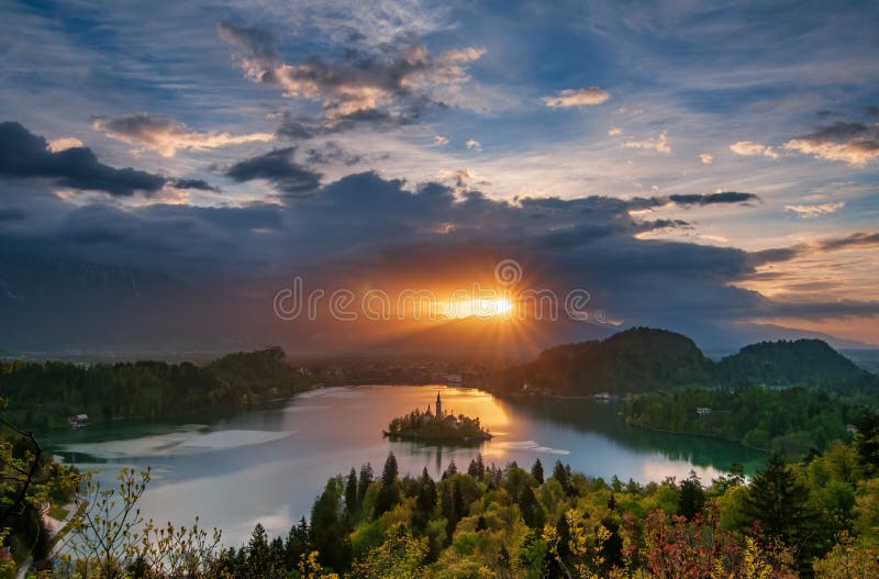 Incredible sunrise over Lake Bled at spring morning. View from Ojstrica Hill, Slovenia. Lake Bled is a popular travel destination and tourist attraction in Slovenia and Alpine region, traveling, dramatic, european, idyll, landscape, picturesque, springtime, summertime, trip, water, stunning, gorgeous, serene, restful, peaceful, tranquility, waterscape, azure, amazing, mountains, calmness, castle, scenery, beam, panorama, magnificent, clouds, range, hills, colourful, woodland, highland, overlooking, island, church, assumption, daybreak, aurora, dawn, daylight. Incredible sunrise over Lake Bled at spring morning. View from Ojstrica Hill, Slovenia. Lake Bled is a popular travel destination and tourist attraction in Slovenia and Alpine region, traveling, dramatic, european, idyll, landscape, picturesque, springtime, summertime, trip, water, stunning, gorgeous, serene, restful, peaceful, tranquility, waterscape, azure, amazing, mountains, calmness, castle, scenery, beam, panorama, magnificent, clouds, range, hills, colourful, woodland, highland, overlooking, island, church, assumption, daybreak, aurora, dawn, daylight