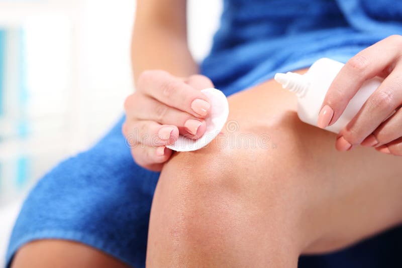 Female disinfects the wound on his knee pouring with oxygenated water. Female disinfects the wound on his knee pouring with oxygenated water.