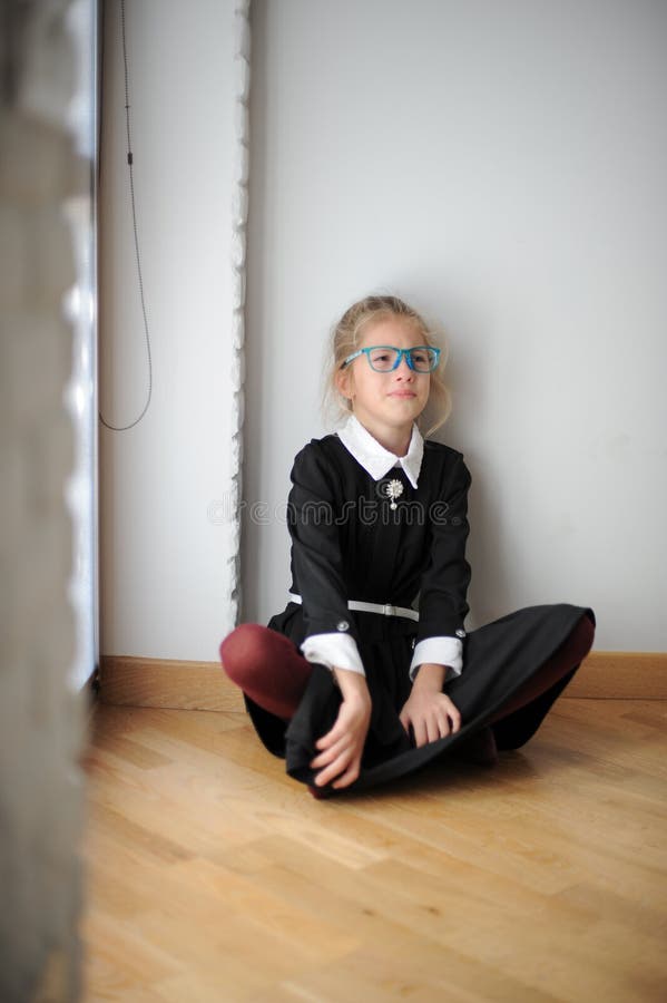 Frustration state of mind crying upset little girl in glasses and school uniform sitting on floor near window. Frustration state of mind crying upset little girl in glasses and school uniform sitting on floor near window