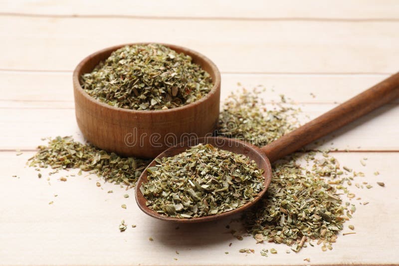 Αποξηραμένο oregano σε κουτάλι και μπολ σε ξύλινο τραπέζι σε κοντινή θέα στοκ εικόνες
