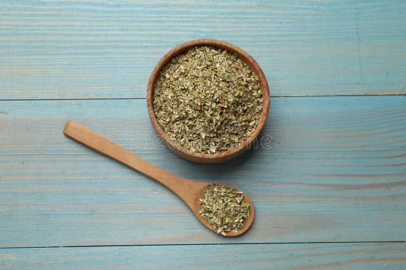 Αποξηραμένο oregano σε μπολ και κουτάλι σε ανοιχτή μπλε ξύλινη επιφάνεια στοκ εικόνες
