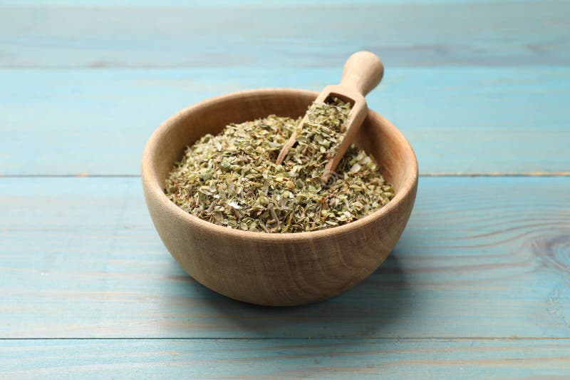 Αποξηραμένο oregano σε μπολ και κουτάλι σε ανοιχτό μπλε ξύλινο τραπέζι κοντά στοκ φωτογραφία με δικαίωμα ελεύθερης χρήσης