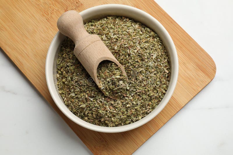 Αποξηραμένο oregano σε μπολ και κουτάλι σε λευκό τραπέζι πάνω όψη στοκ εικόνες