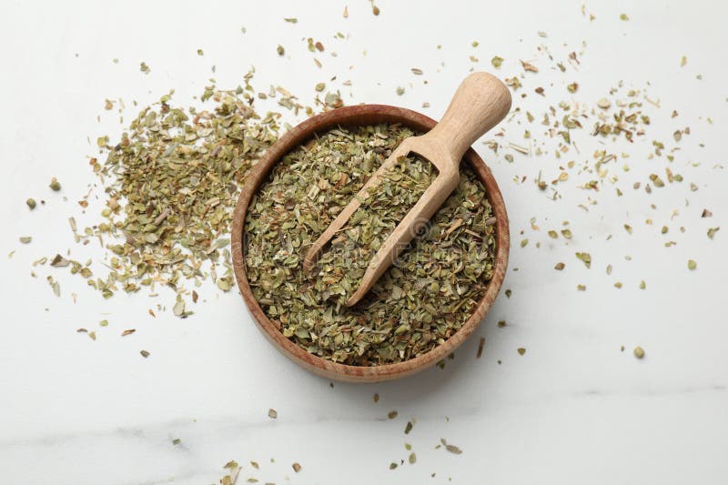Αποξηραμένο oregano σε μπολ και κουτάλι σε λευκό τραπέζι πάνω όψη στοκ εικόνες