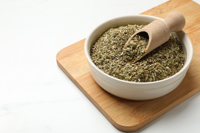 Αποξηραμένο oregano σε μπολ και σκούπα σε λευκό τραπέζι στοκ φωτογραφίες