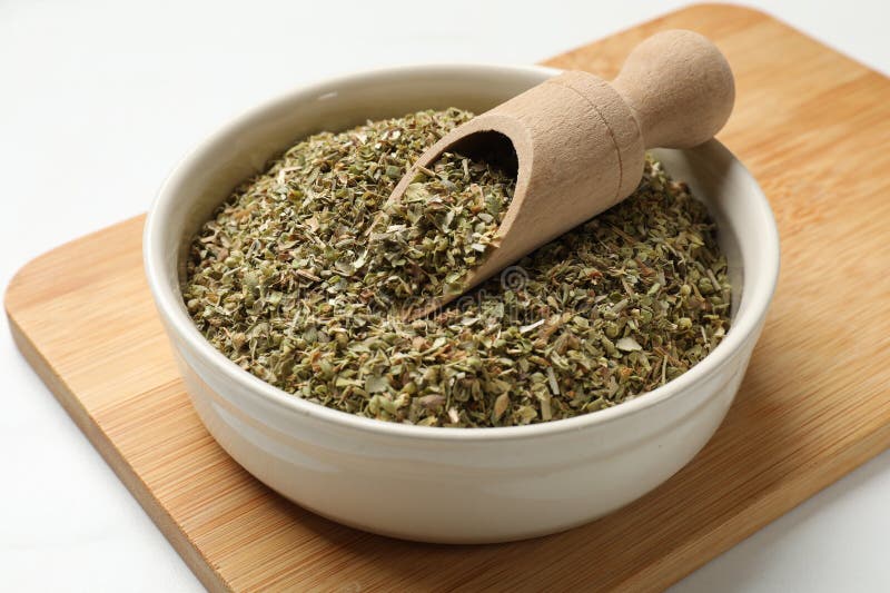 Αποξηραμένο oregano σε μπολ και σκούπα σε λευκό τραπέζι στοκ φωτογραφία με δικαίωμα ελεύθερης χρήσης