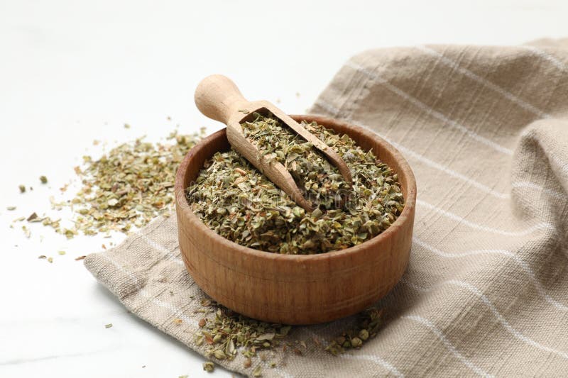 Αποξηραμένο oregano σε μπολ και σκούπα σε λευκό τραπέζι στοκ εικόνες με δικαίωμα ελεύθερης χρήσης