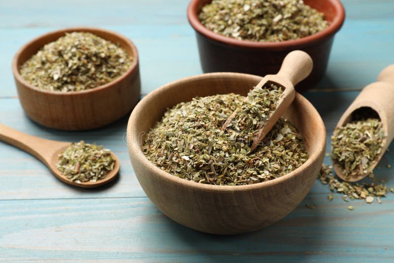 Αποξηραμένο oregano σε μπουλόνια και κουτάλι σε ανοιχτό μπλε ξύλινο τραπέζι στοκ εικόνες με δικαίωμα ελεύθερης χρήσης