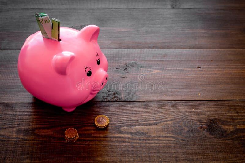 αποταμίευση Moneybox στη μορφή του χοίρου με τα τραπεζογραμμάτια που περιέρχονται σε το κοντά στα νομίσματα στο σκοτεινό ξύλινο δ στοκ φωτογραφία με δικαίωμα ελεύθερης χρήσης αποταμίευση Moneybox στη μορφή του χοίρου με τα τραπεζογραμμάτια που περιέρχονται σε το κοντά στα νομίσματα στο σκοτεινό ξύλινο δ στοκ φωτογραφία με δικαίωμα ελεύθερης χρήσης