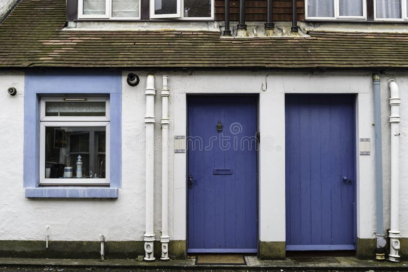 View of a Low Largo village house facade with 2 blue entrance doors a white window. View of a Low Largo village house facade with 2 blue entrance doors a white window