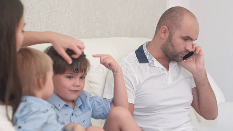 Αρκετά νέο παιχνίδι μητέρων με τα μικρά παιδιά της ενώ μπαμπάς που είναι πολυάσχολος στο τηλέφωνο στοκ φωτογραφία με δικαίωμα ελεύθερης χρήσης Αρκετά νέο παιχνίδι μητέρων με τα μικρά παιδιά της ενώ μπαμπάς που είναι πολυάσχολος στο τηλέφωνο στοκ φωτογραφία με δικαίωμα ελεύθερης χρήσης