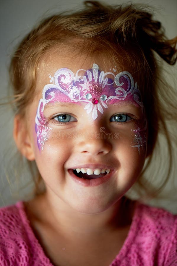 Pretty exciting blue-eyed girl of 2 years with a pink face painting. Pretty exciting blue-eyed girl of 2 years with a pink face painting