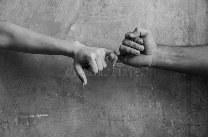 Αρσενικά και θηλυκά χέρια το ένα σχετικά με το άλλο με τα μικρά δάχτυλα στοκ εικόνα