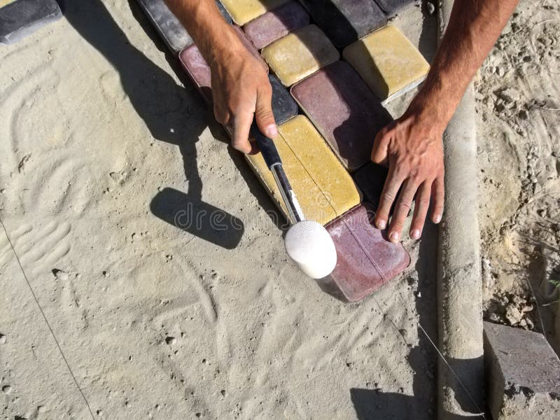 Αρσενικά χέρια που χτυπούν με μια λαστιχένια σφύρα στις πολύχρωμες πλάκες επίστρωσης - τοπ άποψη στοκ εικόνες Αρσενικά χέρια που χτυπούν με μια λαστιχένια σφύρα στις πολύχρωμες πλάκες επίστρωσης - τοπ άποψη στοκ εικόνες
