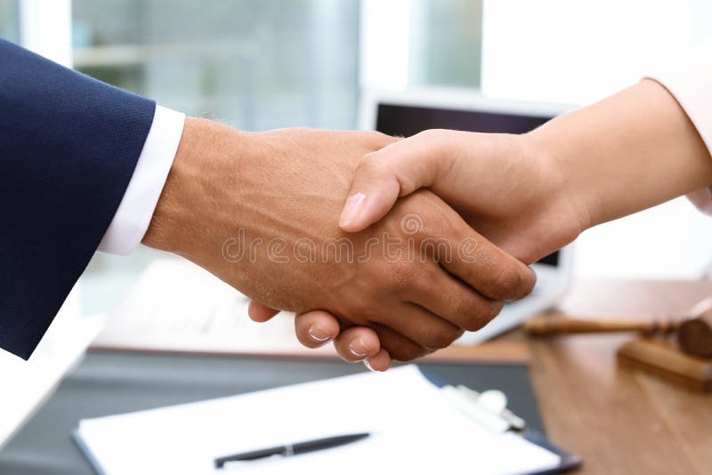 Αρσενικά χέρια τινάγματος δικηγόρων με τη γυναίκα πέρα από τον πίνακα στοκ εικόνες