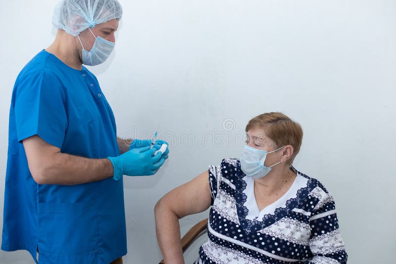 αρσενική νοσοκόμα κάνει ένεση σε ηλικιωμένη γυναίκα εμβολιασμό στοκ εικόνες