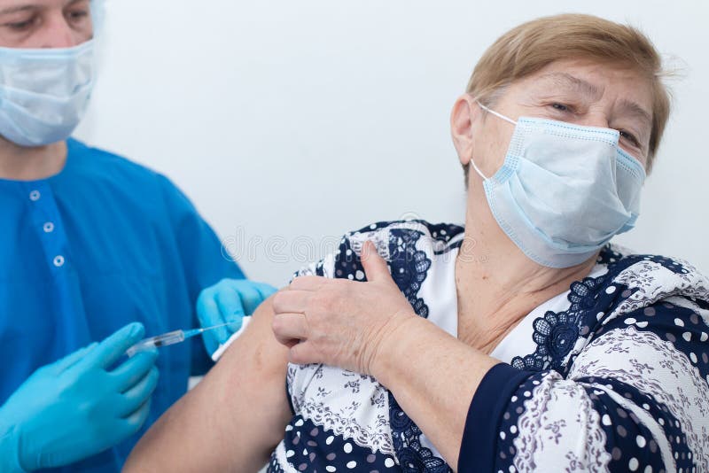 αρσενική νοσοκόμα κάνει ένεση σε ηλικιωμένη γυναίκα εμβολιασμό στοκ εικόνα