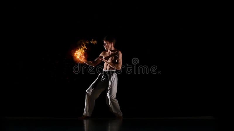 αρσενικό kyokushinkai karate που εκτελεί kata σε μαύρο στούντιο. ο αθλητής αποδίδει γροθιές γροθιές. χτυπήματα με