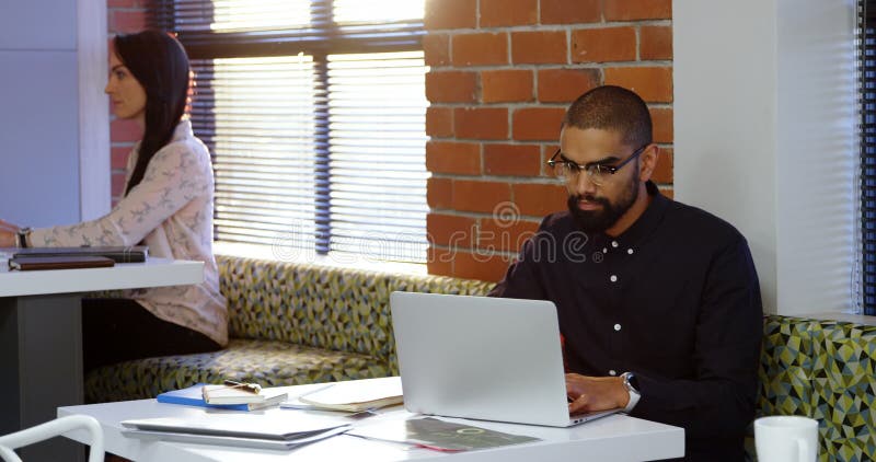 Αρσενικό εκτελεστικό χρησιμοποιώντας lap-top στην καφετέρια 4k γραφείων