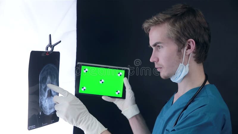 Αρσενικός γιατρός που εξετάζει μια των ακτίνων X εικόνα, που χρησιμοποιεί την πράσινη ταμπλέτα οθόνης