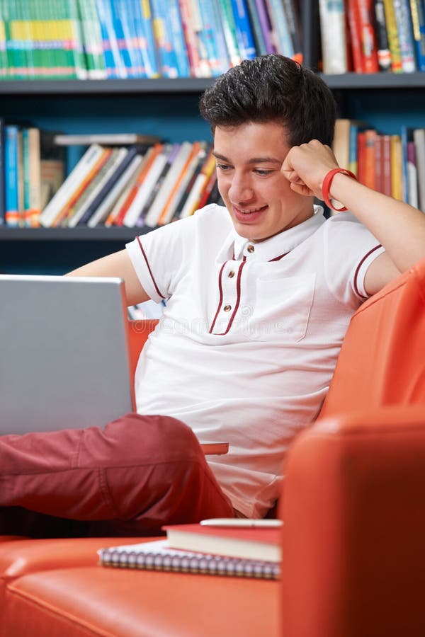 Αρσενικός εφηβικός σπουδαστής με το lap-top που λειτουργεί στη βιβλιοθήκη στοκ εικόνα Αρσενικός εφηβικός σπουδαστής με το lap-top που λειτουργεί στη βιβλιοθήκη στοκ εικόνα