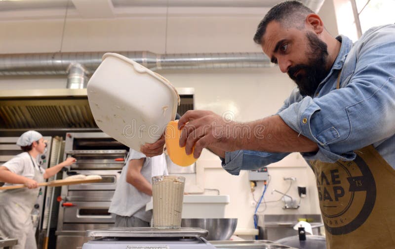 Αρτοποιοί που κατασκευάζουν τις χειροποίητες φραντζόλες του ψωμιού σε ένα οικογενειακό αρτοποιείο που διαμορφώνει τη ζύμη στις μο στοκ φωτογραφία με δικαίωμα ελεύθερης χρήσης Αρτοποιοί που κατασκευάζουν τις χειροποίητες φραντζόλες του ψωμιού σε ένα οικογενειακό αρτοποιείο που διαμορφώνει τη ζύμη στις μο στοκ φωτογραφία με δικαίωμα ελεύθερης χρήσης