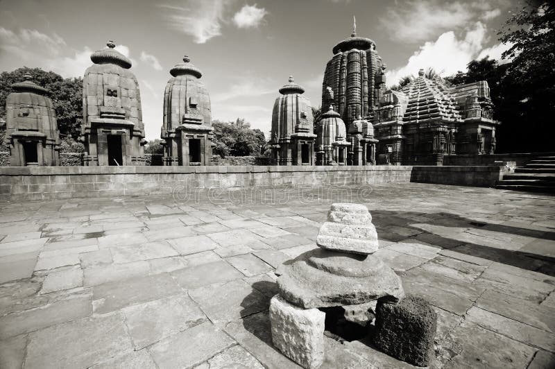 Stone shrine inside temple yard with temples in the background in a vintage black and white horizontal image. Shot at 10th century Mukteshwar Siddheshwar temple in Orissa, India. Stone shrine inside temple yard with temples in the background in a vintage black and white horizontal image. Shot at 10th century Mukteshwar Siddheshwar temple in Orissa, India.