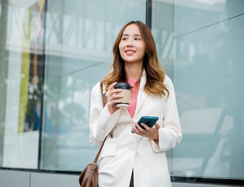 ασιάτισσα επιχειρηματίας με smartphone και καφέ μπροστά στο δρόμο στοκ φωτογραφία με δικαίωμα ελεύθερης χρήσης