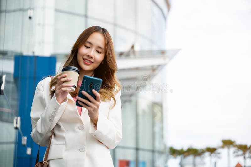 ασιάτισσα επιχειρηματίας με smartphone και καφέ μπροστά στο κτίριο του δρόμου κοντά στο γραφείο στοκ φωτογραφία με δικαίωμα ελεύθερης χρήσης