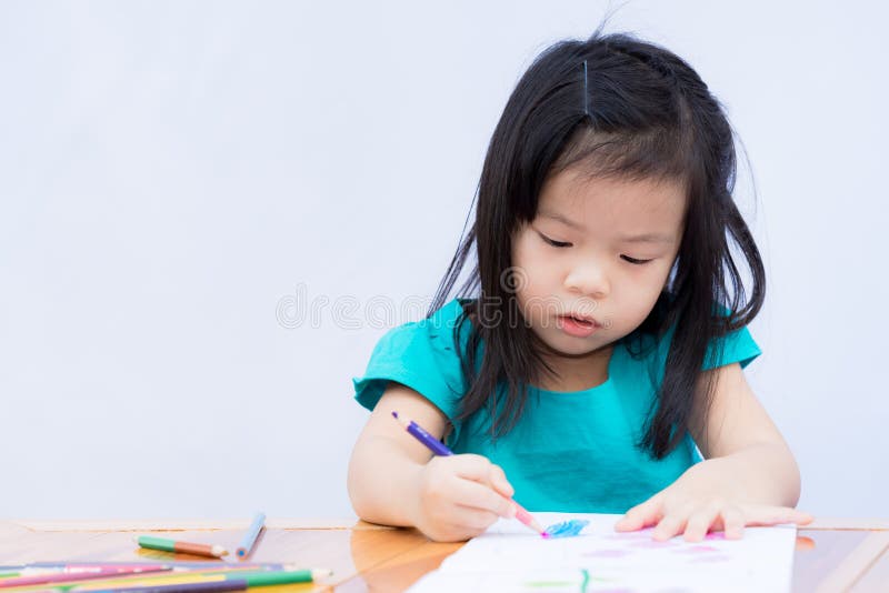 Asian girl is sitting and doing homework. Child use wooden colors to paint on drawing book. Happy children to make art. Practice concentration and imagination. Kid independent time. Baby 3-4 years old. Asian girl is sitting and doing homework. Child use wooden colors to paint on drawing book. Happy children to make art. Practice concentration and imagination. Kid independent time. Baby 3-4 years old.