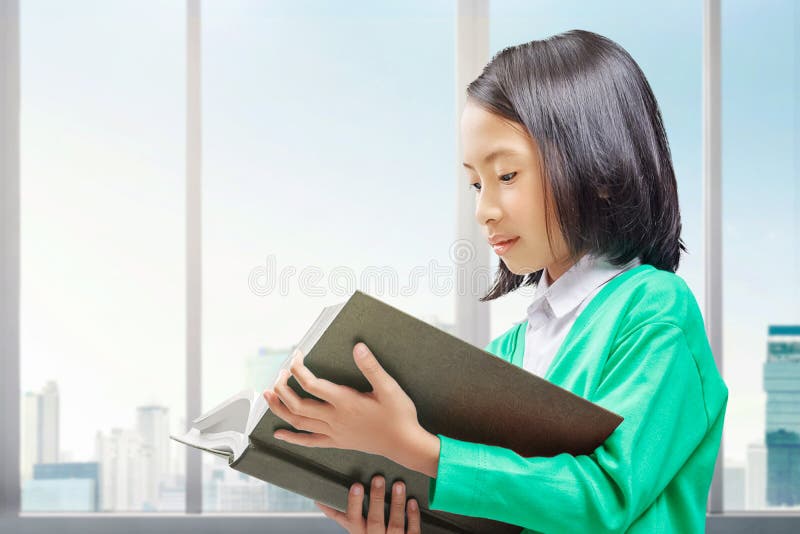 ασιάτισσα κοριτσάκι που στέκεται και διαβάζει το βιβλίο στο σπίτι