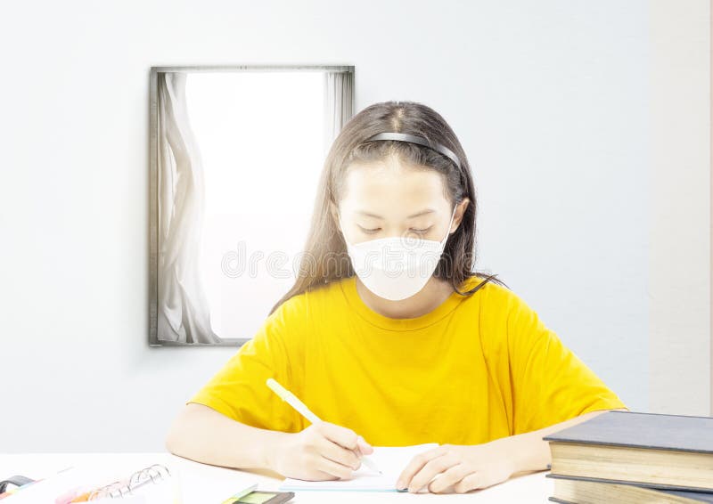 ασιάτισσα κοριτσάκι που φοράει τη μάσκα και κάνει τα μαθήματά της στο σπίτι