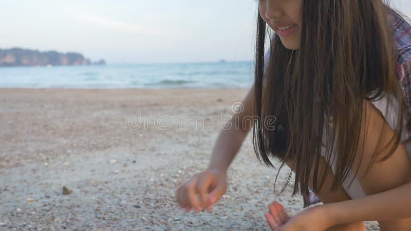 Ασιατικά κοχύλια επιλογής παιδιών στην παραλία