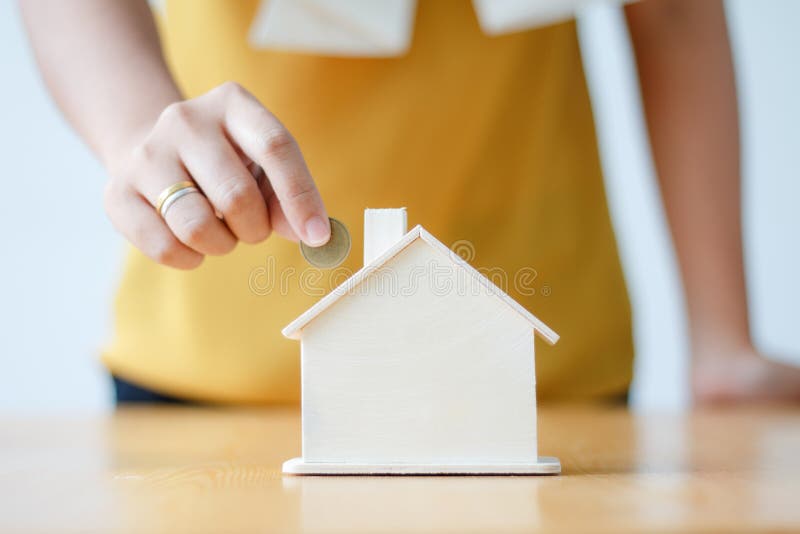 Ασιατική γυναίκα που υποβάλλει το νόμισμα χρημάτων στη piggy μεταφορά s τραπεζών σπιτιών στοκ φωτογραφία με δικαίωμα ελεύθερης χρήσης Ασιατική γυναίκα που υποβάλλει το νόμισμα χρημάτων στη piggy μεταφορά s τραπεζών σπιτιών στοκ φωτογραφία με δικαίωμα ελεύθερης χρήσης