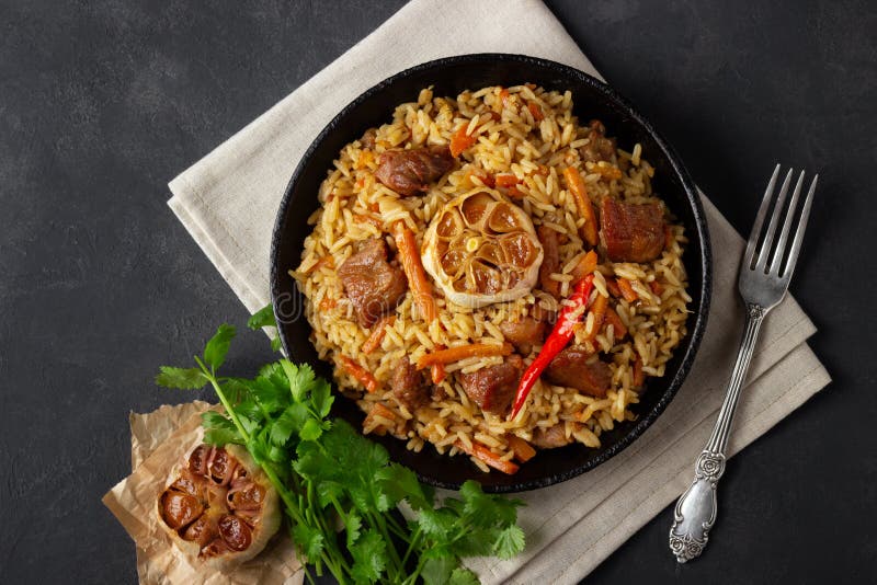 Ασιατική κουζίνα Του Ουζμπεκιστάν pilaf ή plov από το ρύζι και το κρέας σε ένα τηγάνι χυτοσιδήρου στοκ φωτογραφία Ασιατική κουζίνα Του Ουζμπεκιστάν pilaf ή plov από το ρύζι και το κρέας σε ένα τηγάνι χυτοσιδήρου στοκ φωτογραφία