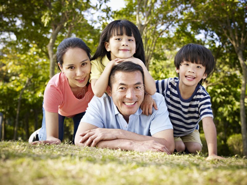 Happy asian family with two children taking a family photo outdoors in a park. Happy asian family with two children taking a family photo outdoors in a park.