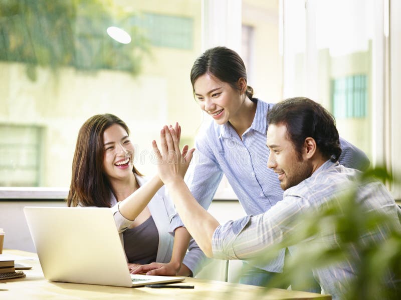 Young asian business person giving coworker high five in office celebrating achievement and success. Young asian business person giving coworker high five in office celebrating achievement and success.