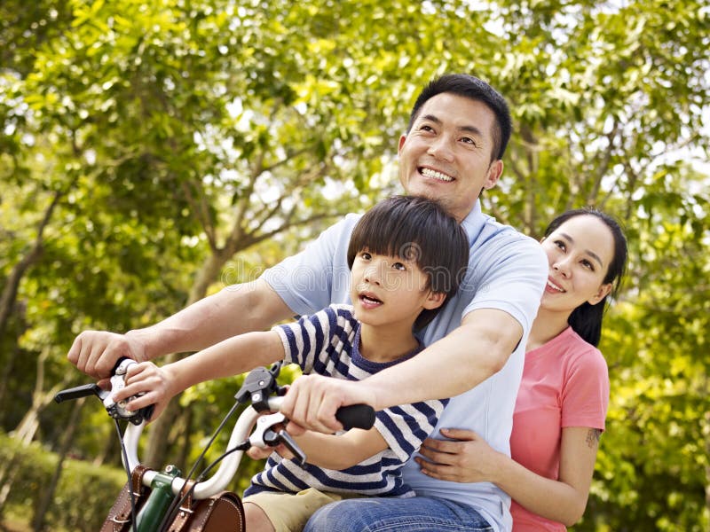 Ασιατικό οικογενειακό οδηγώντας ποδήλατο στο πάρκο