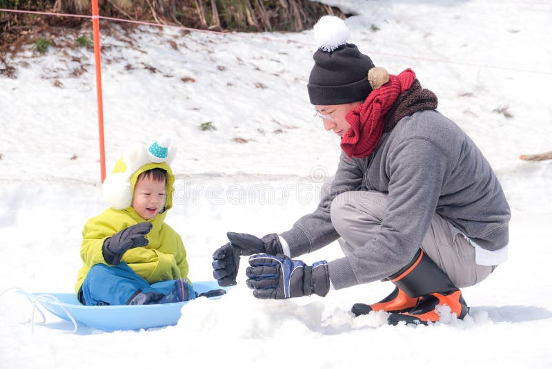 Asian Father and cute smiling little 2-3 years old toddler boy child playing happily in snow, Family travel, Relax and fun winter holiday vacation with child, winter season concept. Asian Father and cute smiling little 2-3 years old toddler boy child playing happily in snow, Family travel, Relax and fun winter holiday vacation with child, winter season concept